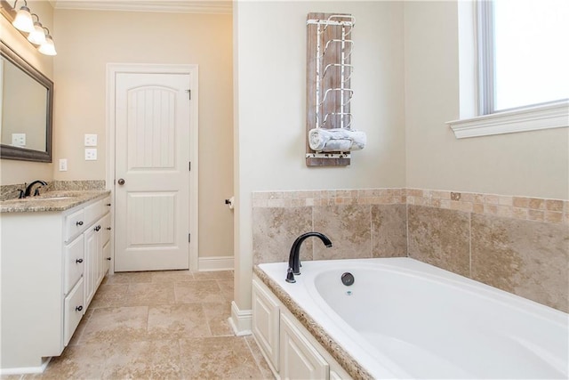 full bath featuring a garden tub, crown molding, vanity, and baseboards