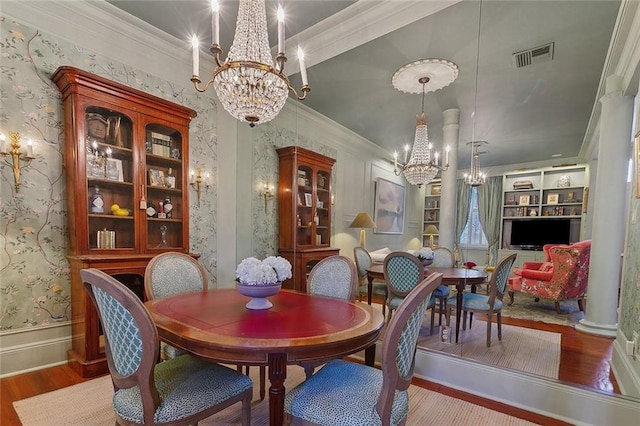 dining room featuring a chandelier, wood finished floors, visible vents, and wallpapered walls