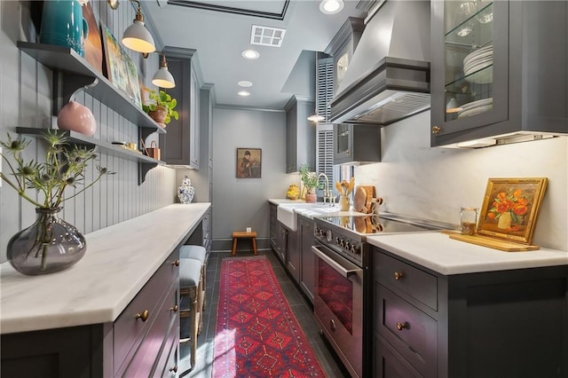 kitchen featuring light countertops, wall chimney range hood, high end stainless steel range, and visible vents