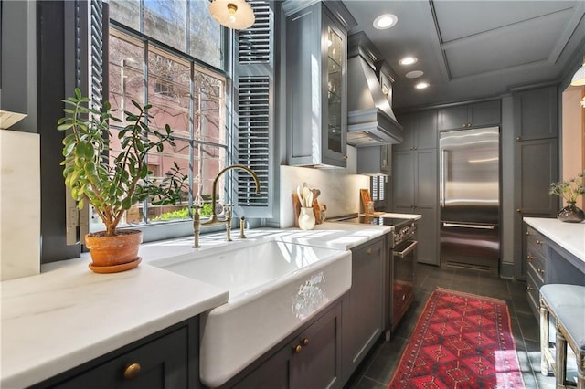 kitchen featuring premium appliances, recessed lighting, light countertops, custom range hood, and a sink