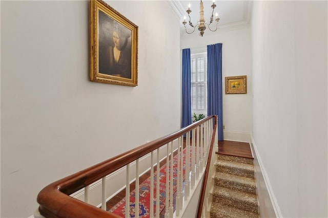 hallway with a chandelier, crown molding, and baseboards