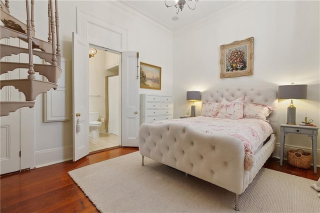 bedroom with crown molding, an inviting chandelier, ensuite bathroom, wood finished floors, and baseboards