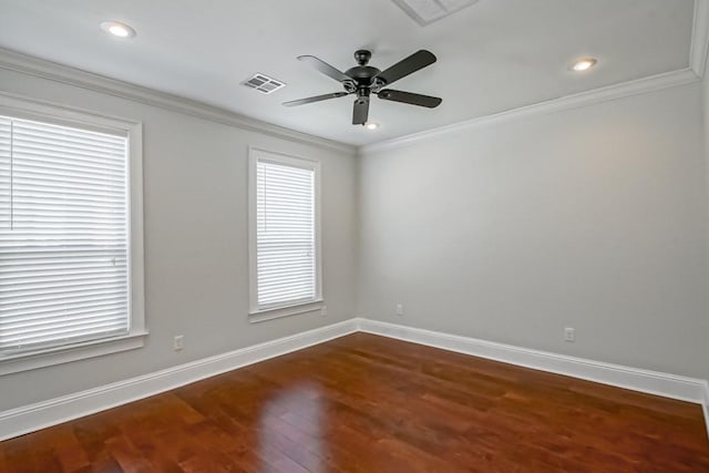 spare room with dark wood-style floors, visible vents, crown molding, and baseboards