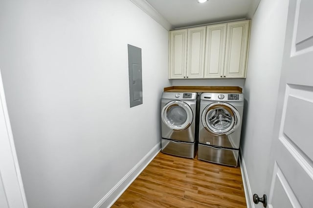 washroom featuring cabinet space, electric panel, baseboards, wood finished floors, and independent washer and dryer