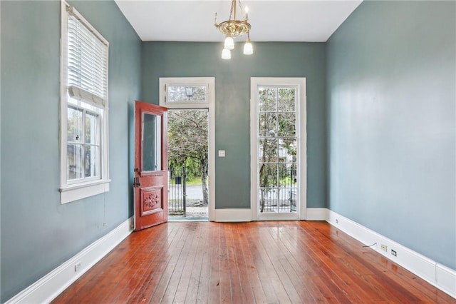 entryway featuring an inviting chandelier, baseboards, and hardwood / wood-style flooring