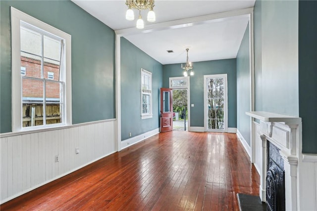 foyer featuring baseboards, visible vents, hardwood / wood-style flooring, a fireplace, and a chandelier