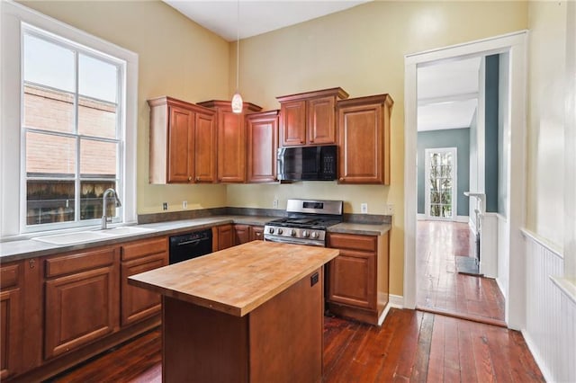 kitchen with butcher block countertops, a sink, dark wood-style floors, black appliances, and pendant lighting