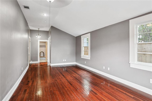 spare room featuring lofted ceiling, baseboards, visible vents, and wood-type flooring