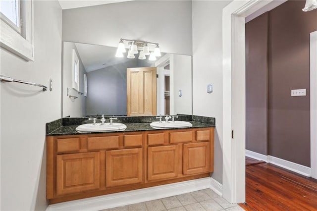 bathroom with double vanity, baseboards, and a sink