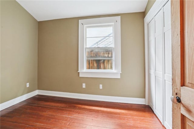 unfurnished bedroom featuring a closet, hardwood / wood-style flooring, and baseboards