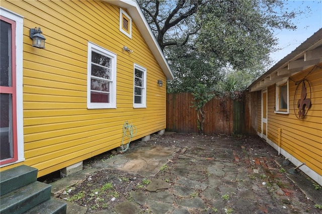 view of side of property featuring entry steps, fence, and a patio