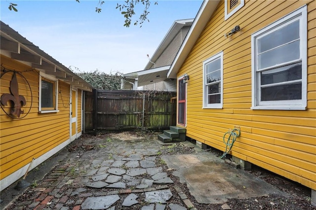 view of side of property featuring entry steps, a patio area, and fence