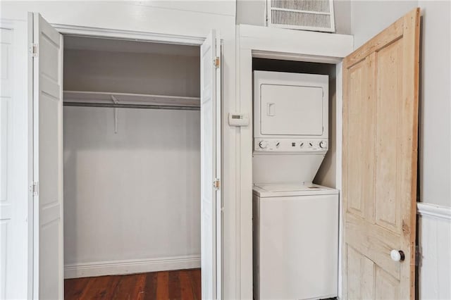 laundry room featuring laundry area, stacked washer / dryer, wood finished floors, visible vents, and baseboards