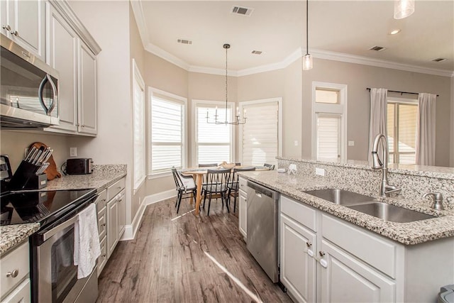 kitchen with visible vents, appliances with stainless steel finishes, a sink, and ornamental molding