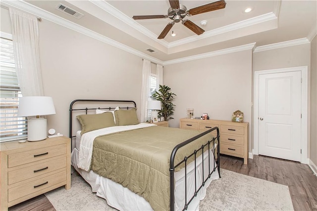 bedroom featuring light wood-style floors, visible vents, and a raised ceiling