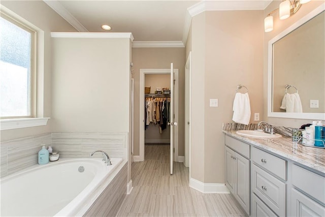 bathroom featuring a garden tub, crown molding, a spacious closet, vanity, and baseboards