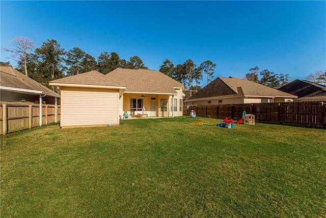 back of property with a fenced backyard and a lawn