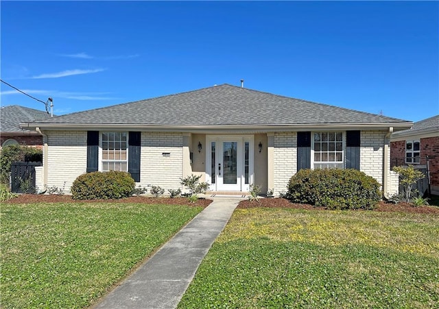 view of front of property with roof with shingles, brick siding, and a front lawn