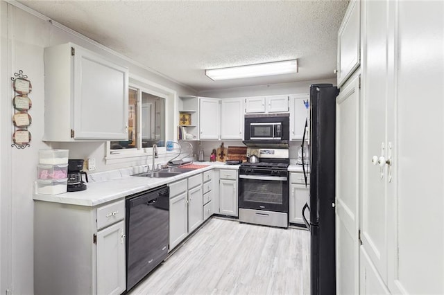 kitchen with light wood finished floors, light countertops, a sink, a textured ceiling, and black appliances