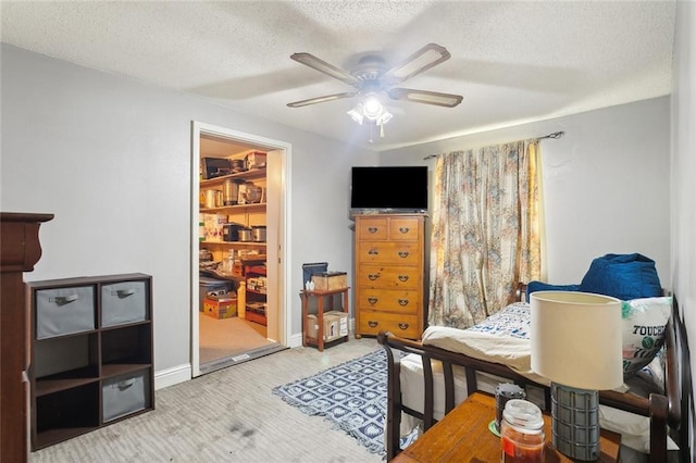 carpeted bedroom with a textured ceiling, ceiling fan, and baseboards