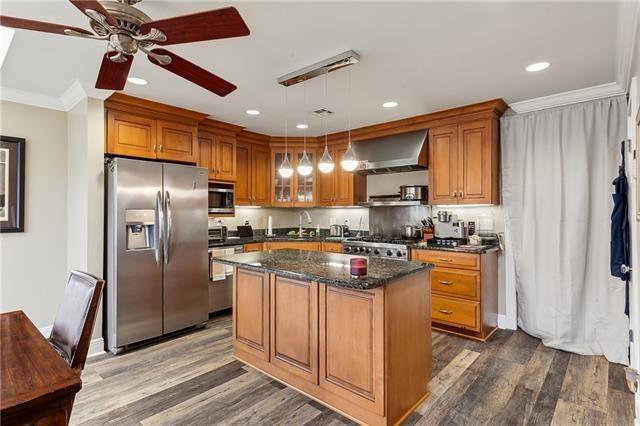 4701 Lake Vista Dr, Metairie, LA 70006 - kitchen with stainless steel appliances, wall chimney exhaust hood, brown cabinetry, a ceiling fan, and recessed lighting