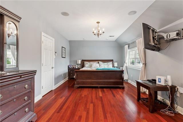 bedroom featuring baseboards, a chandelier, vaulted ceiling, and dark wood-style flooring