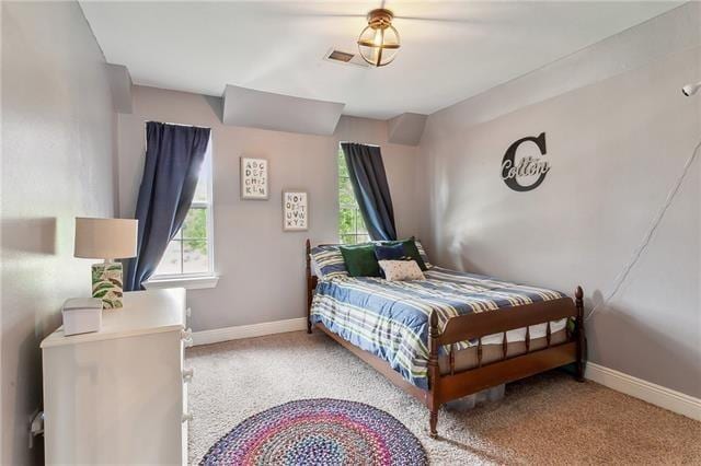 bedroom featuring carpet floors, multiple windows, visible vents, and baseboards