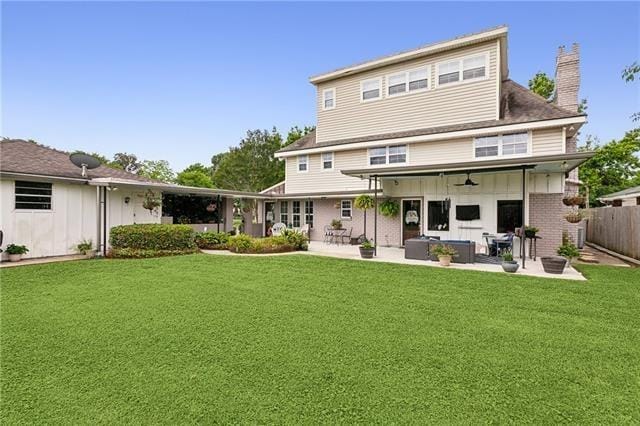 rear view of property with a yard, a patio, a chimney, and fence