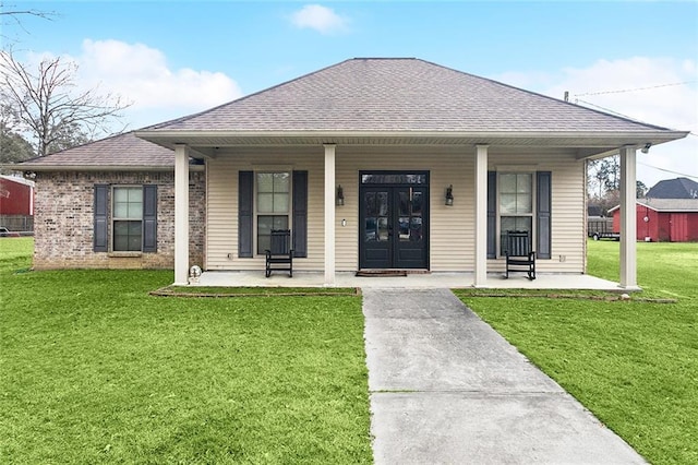 bungalow-style house with a shingled roof, a front yard, covered porch, and brick siding