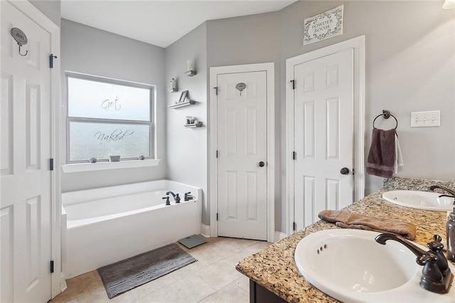 bathroom with double vanity, a garden tub, tile patterned flooring, and a sink