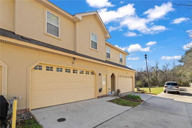 view of front of property featuring a garage, concrete driveway, and stucco siding