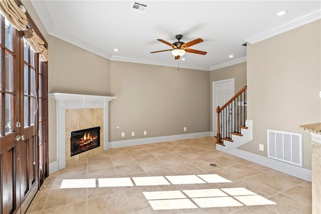 unfurnished living room featuring stairway, a tiled fireplace, visible vents, and crown molding