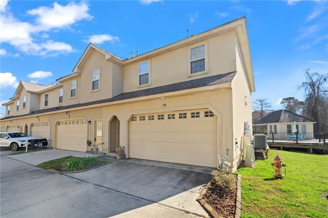 multi unit property with a garage, driveway, central air condition unit, and stucco siding