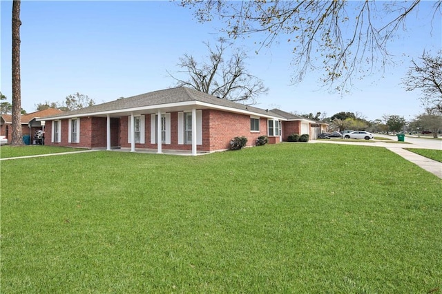 view of side of home featuring a garage, a yard, brick siding, and driveway