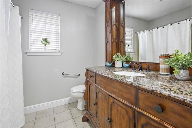 bathroom featuring toilet, vanity, a wealth of natural light, and tile patterned floors