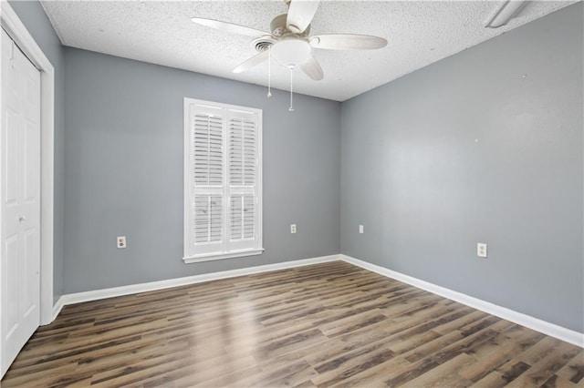 unfurnished bedroom with a textured ceiling, a closet, baseboards, and wood finished floors