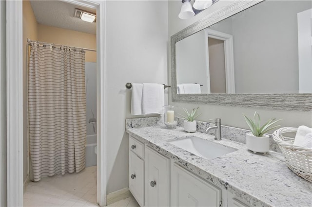 bathroom with a textured ceiling, vanity, and shower / tub combo with curtain