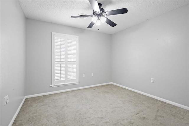 empty room with a textured ceiling, carpet, a ceiling fan, and baseboards