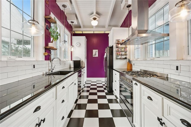 kitchen with dark floors, island exhaust hood, dark countertops, appliances with stainless steel finishes, and a sink