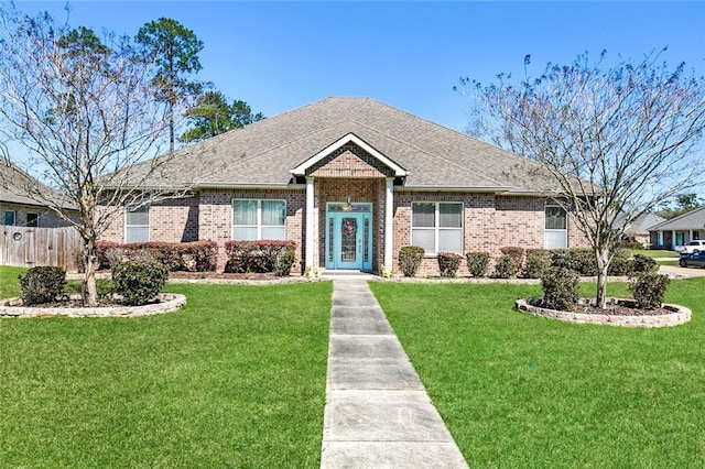 view of front facade featuring brick siding, fence, and a front lawn