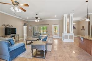 living room with baseboards, decorative columns, arched walkways, and a ceiling fan