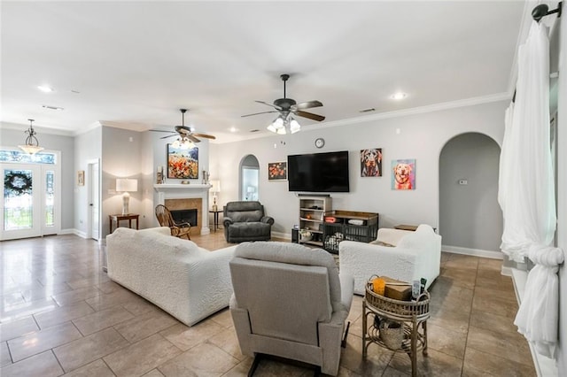 living area with arched walkways, ornamental molding, a fireplace, and baseboards