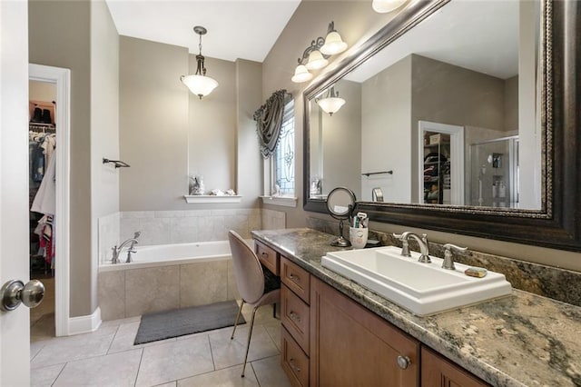 full bath with a walk in closet, a garden tub, a shower stall, vanity, and tile patterned flooring