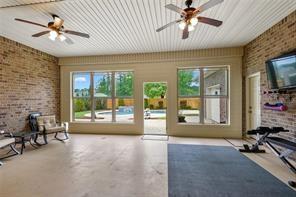 interior space with concrete flooring, brick wall, and ceiling fan