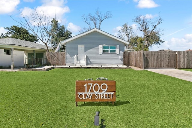 rear view of house featuring fence and a lawn