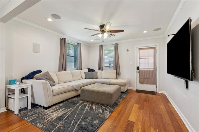 living area with wood finished floors, a ceiling fan, baseboards, visible vents, and crown molding