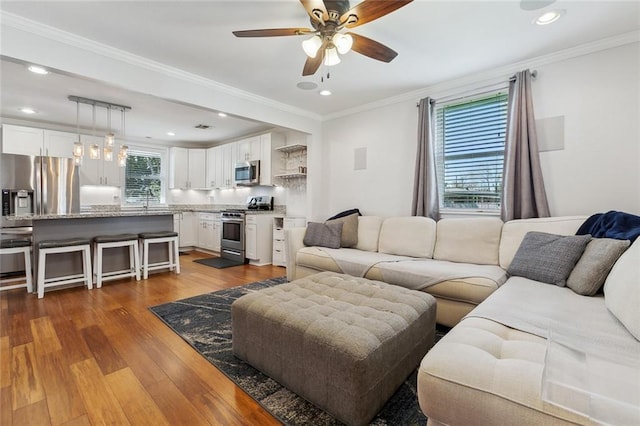 living area featuring dark wood-type flooring, recessed lighting, a ceiling fan, and crown molding