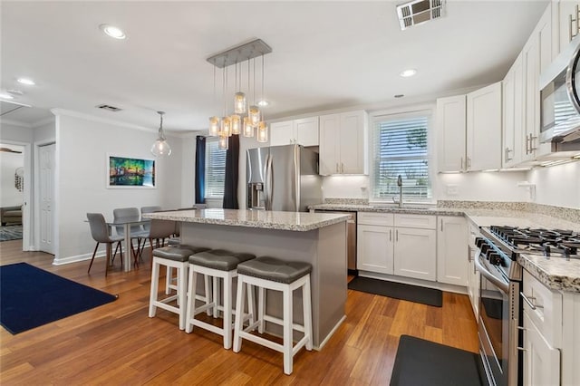 kitchen featuring visible vents, appliances with stainless steel finishes, white cabinets, and ornamental molding