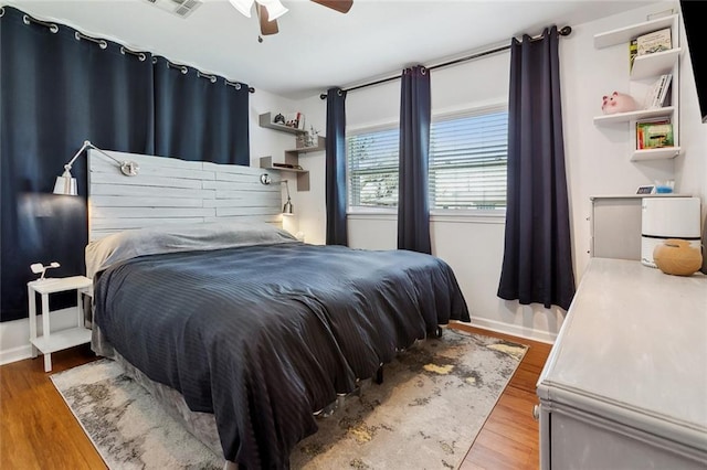 bedroom featuring a ceiling fan, baseboards, and wood finished floors