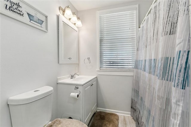 bathroom featuring baseboards, toilet, a shower with curtain, wood finished floors, and vanity